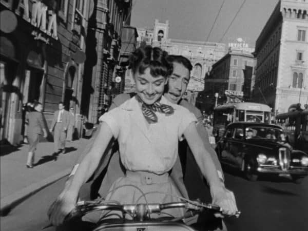 A princess and an american reporter see rome by vespa in roman holiday.