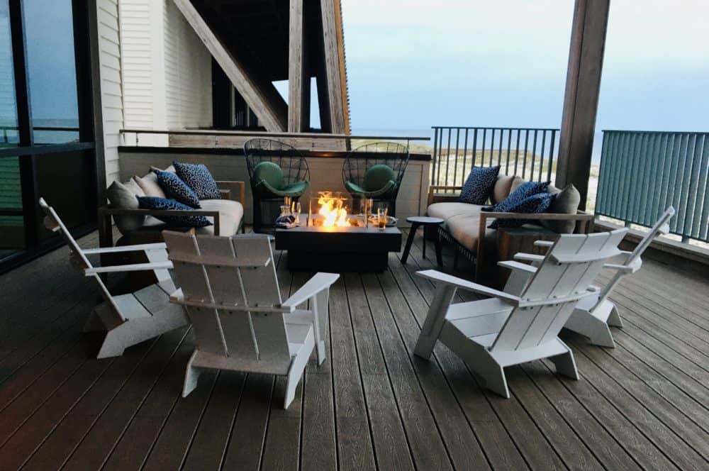 A fireplace and adirondack chairs on the deck outside of perch at the gulf state park lodge.