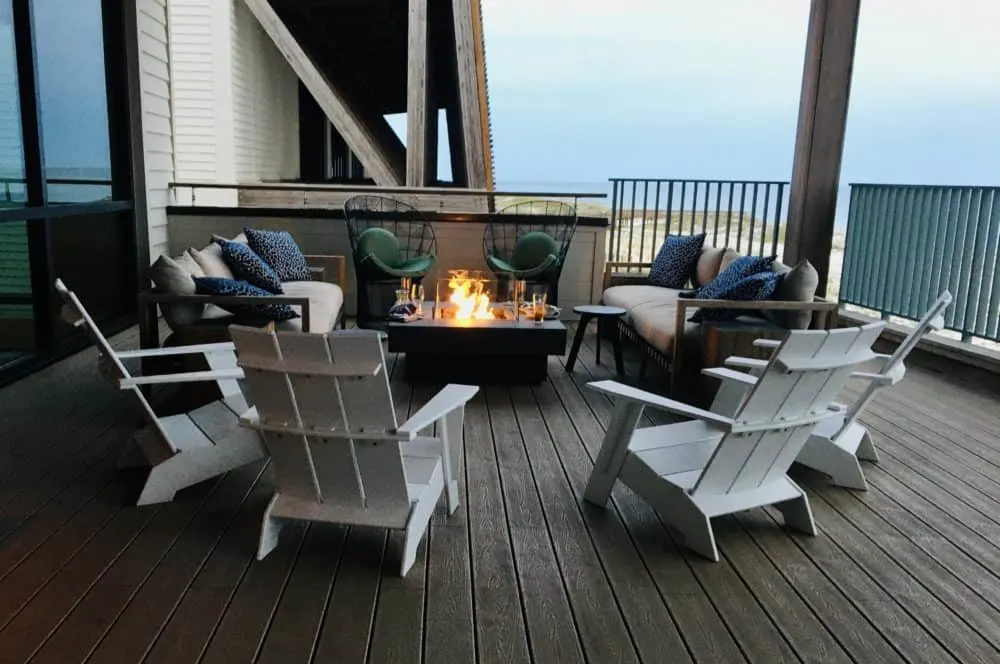 a fireplace and adirondack chairs on the deck outside of perch at the gulf state park lodge.