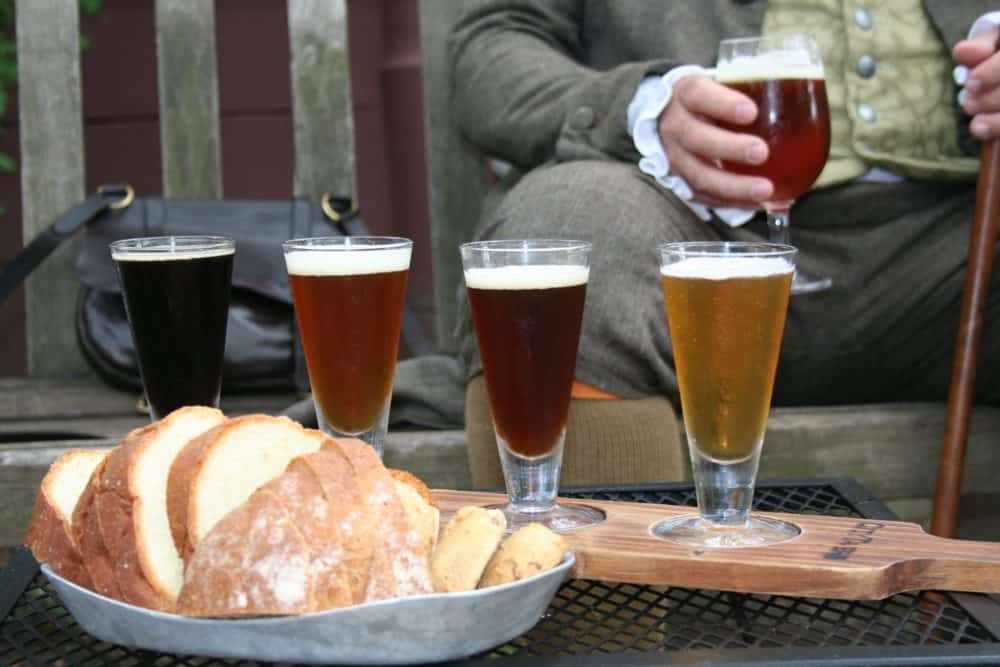 A man in colonial clothes enjoys a flight of beer and housemade bread at city tavern in philadelphia