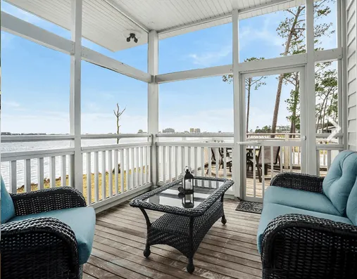 a bright screened in porch with a lake view at the eagles nest cabins in gulf state park