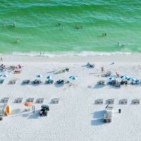 white sand, green surf and beach chairs in a line on the beach at Gulf Shores