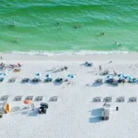 white sand, green surf and beach chairs in a line on the beach at Gulf Shores