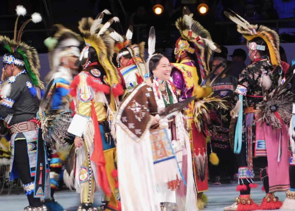 a woman in traditional dress smilling and having fun at the gathering of nations