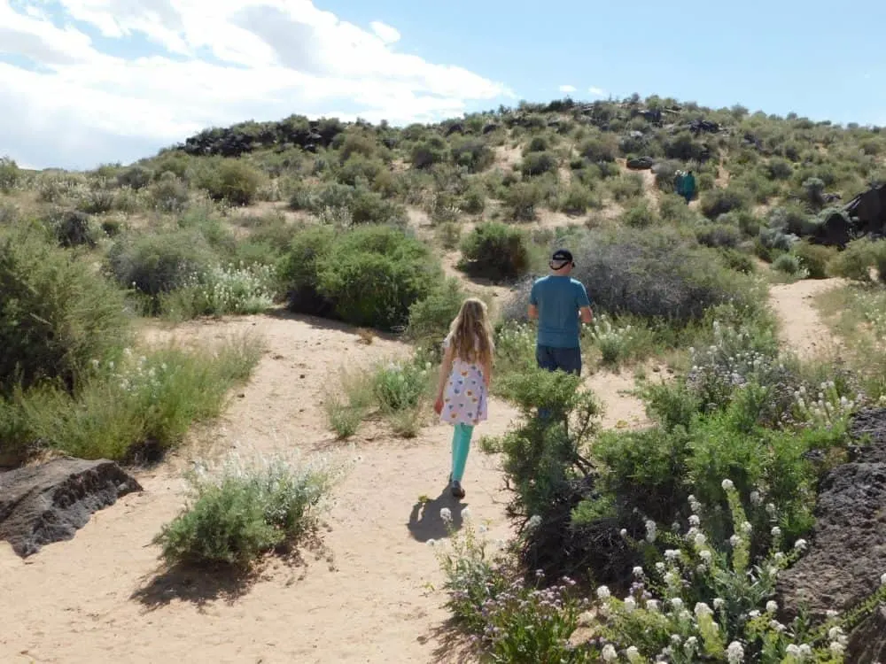 a father and daughter on a hiking trail at petroglyphs national monument