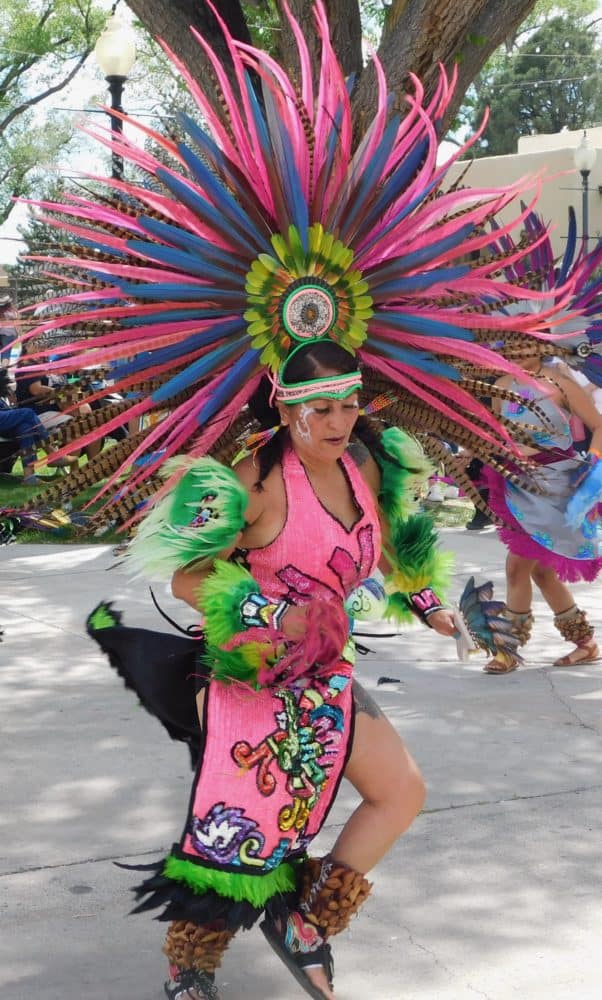 A woman in an enormous bright pink aztec costume dances a the gathering of nations.