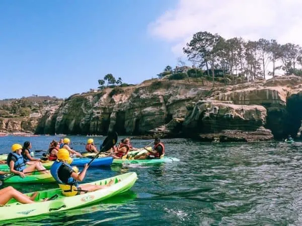 a group of kayaks pausing along the rocky coast off of la jolla, ca