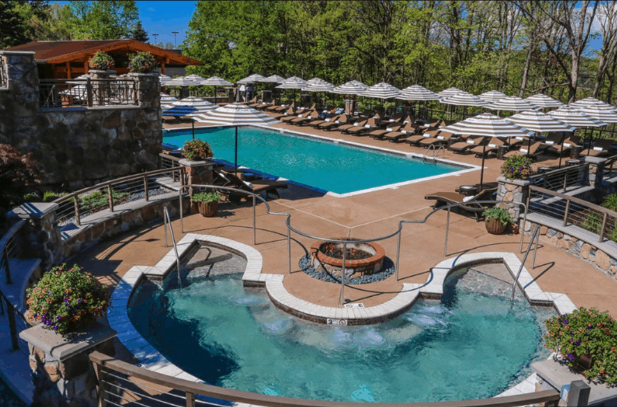 The adult pool, large hot tub and loung chairs with umbrellas at nemacolin woodlands