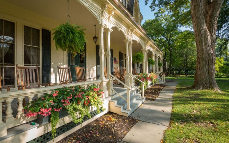 The long porch, rocking chairs and lawn a the family friendly inn at cooperstown.
