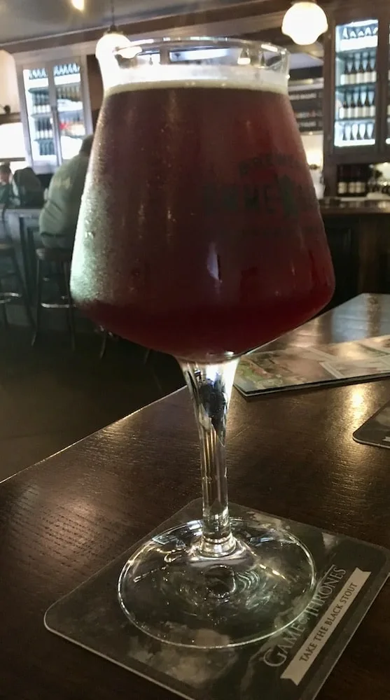 a stem-glass of dark fruit beer on a high-top table at the ommegang brewery.