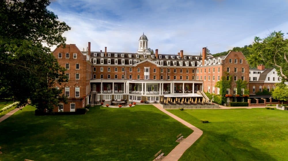 the large, historic otesaga resort features a back porch, patio and lawns.