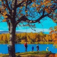A family hikes along a lake in the fall.