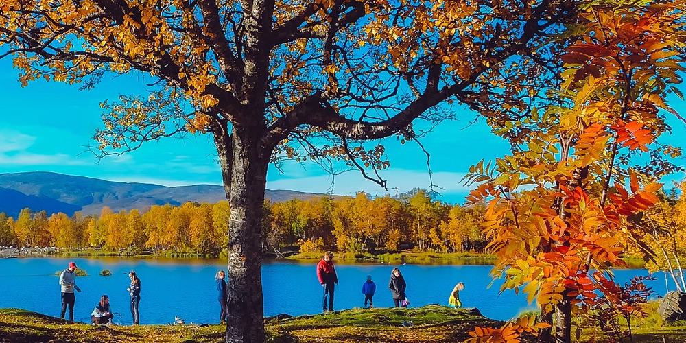 A family hikes along a lake in the fall.