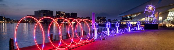 Neon tubes of lights brighten amsterdam's river during its annual december light festival.