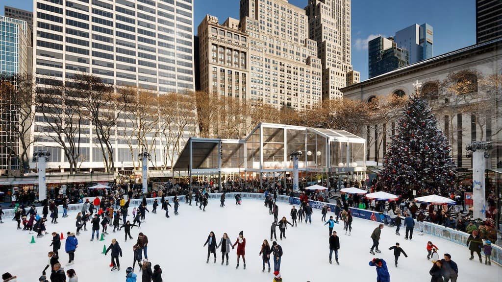 The ice skating rink and winter village shops in bryant park, next to the ny public library.