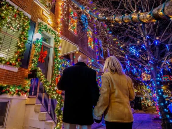 Discover The Best Local Christmas Activities Across The U.s. a couple admires the over-the-top lights on people's rowhouses on 13th street in south philly.