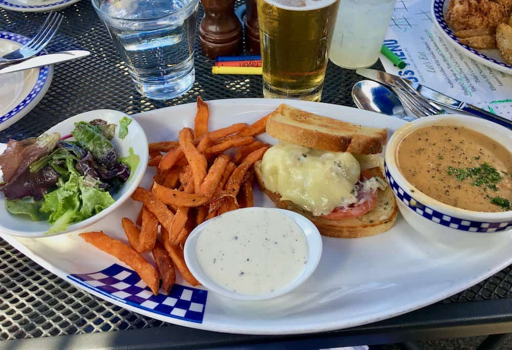 A crab sandwich with sweet potato fries, a green salad and bowl of chowder at duke's seafood.