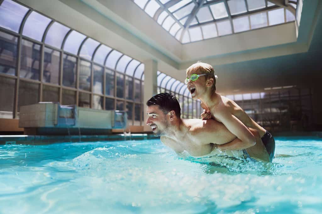 A dad and son splash in the glass atrium and pool at the fairmont olympic seattle.