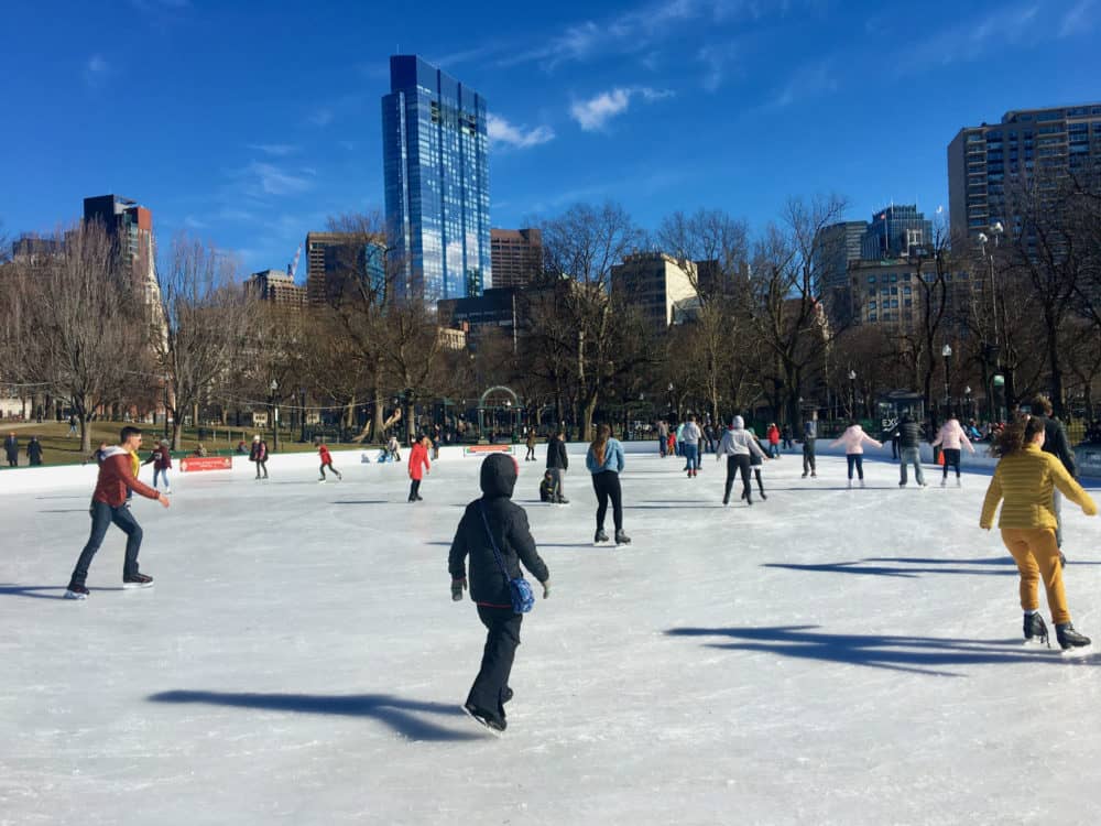 Ice skating on frog pond on the boston common with the city in the background