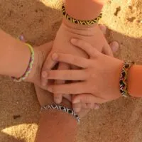 4 hands with friendship bracelets come together the way a blended family does on a familymoon