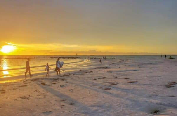 A family walks along a caribbean beach at sunset. They might be on a family honeymoon