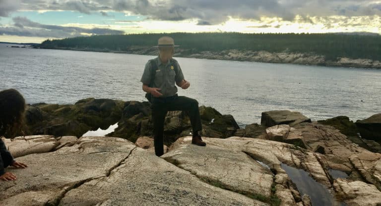 A national park ranger explains acadia's geology from atop some of its coastal boulders.