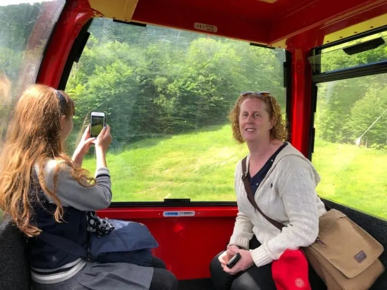 a tween takes photos from the mansfield peak gondola in vermont while her mom admires the view.