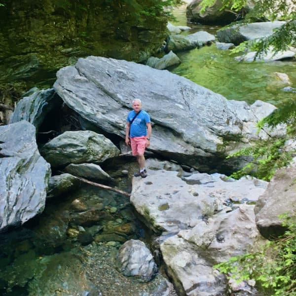 a man poses among the large granite rocks at the bottom of bingham falls.