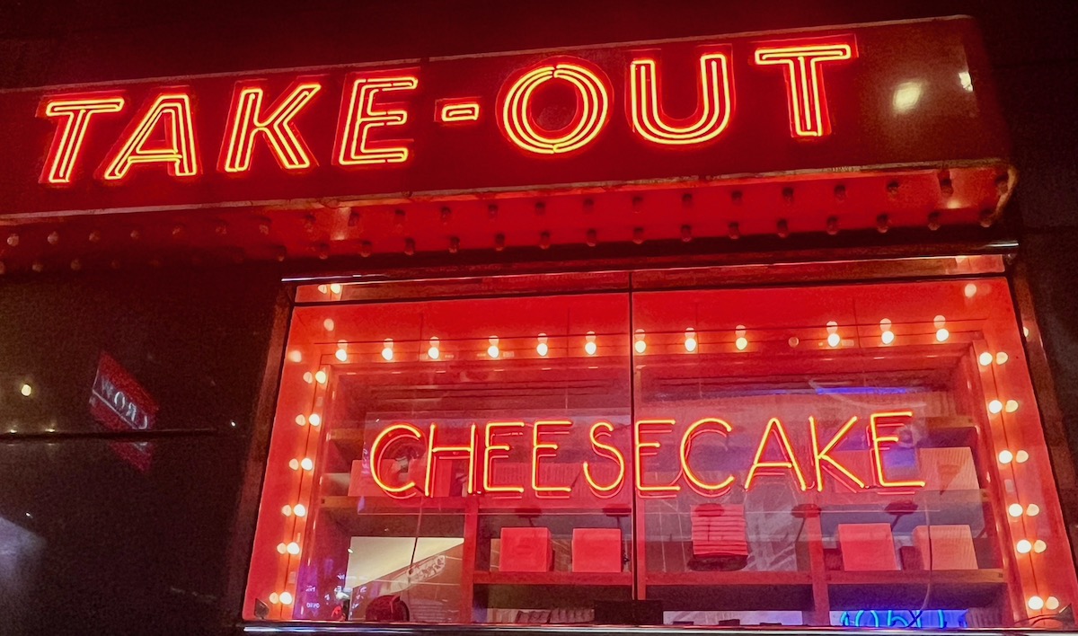 A bright red neon Times Square sign tells you where to get Junior's cheesecake, to stay or to take out.