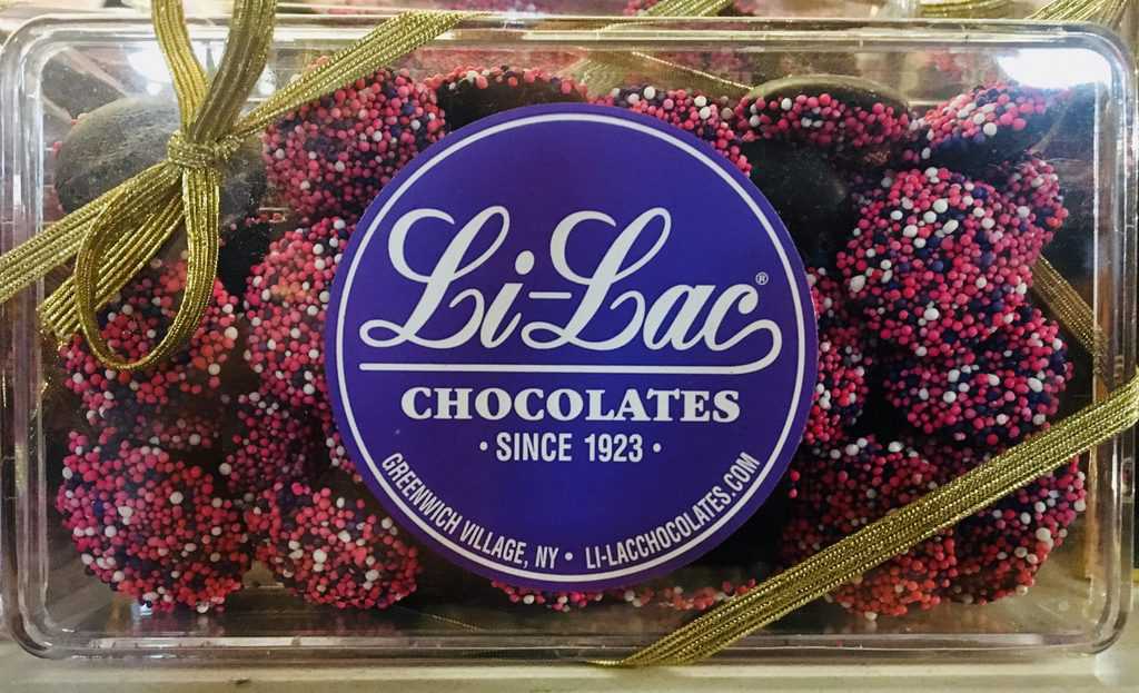 A ribboned box of pink and white dotted non-pareil chocolate from li-lac in nyc.