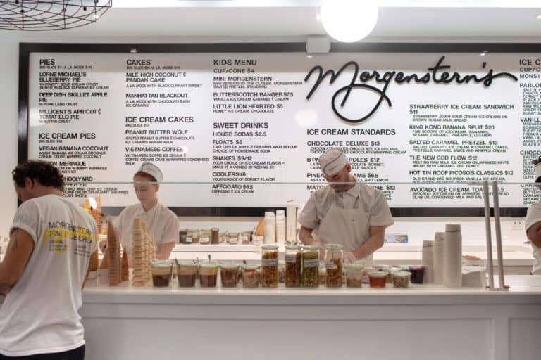 Scoopers in white hats dishing up ice cream with morganstern's giant menu behind them. Judging by the lines, this might be the most popular ice cream in nyc.