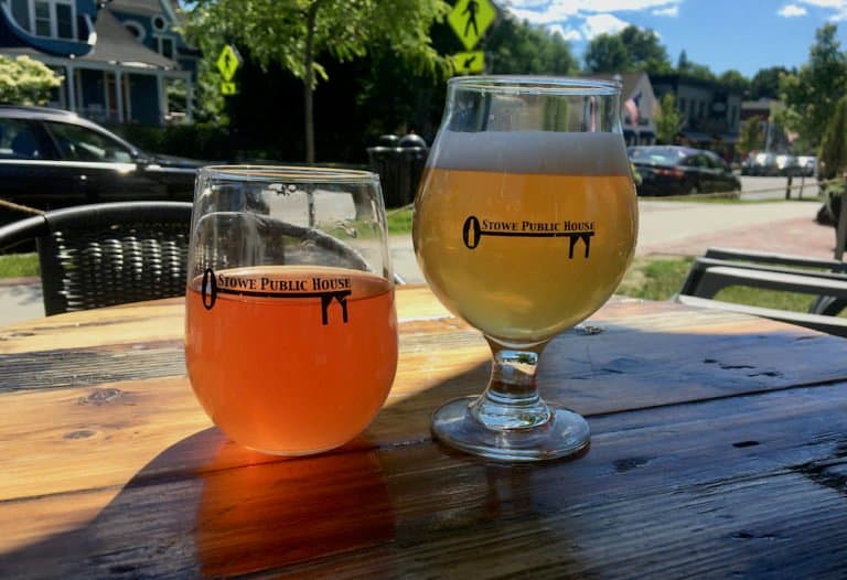 Two glasses of cider and beer at the stowe public house with downtown behind them.