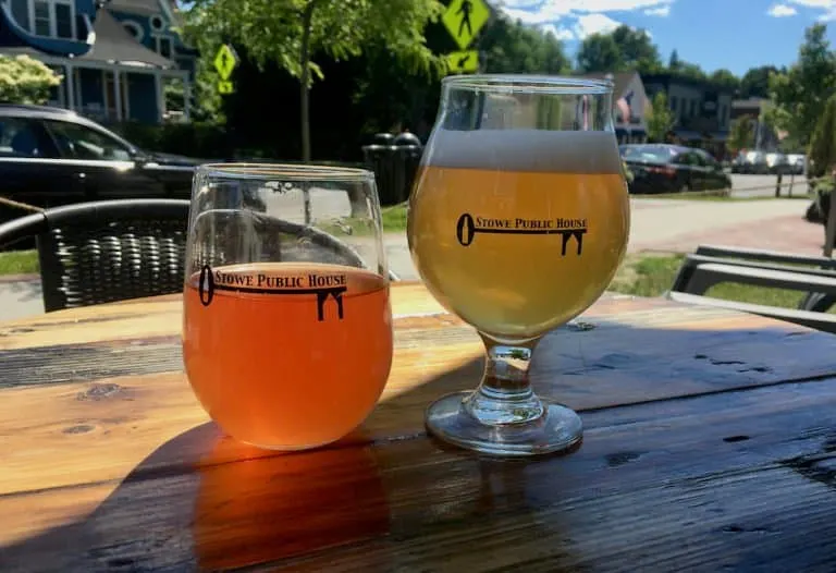 two glasses of cider and beer at the stowe public house with downtown behind them.