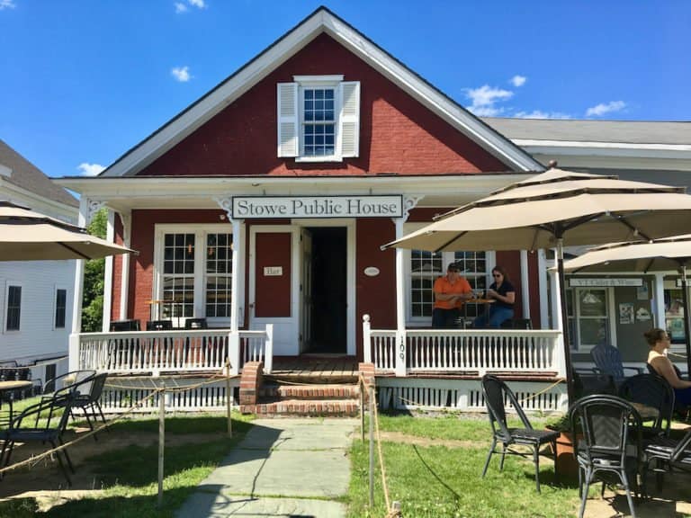 The stowe public house is an old new england house with a porch and outdoor seating right on main street.