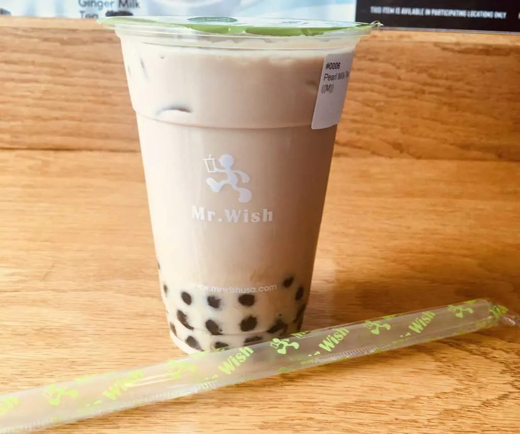 bubble tea, a cold drink with black tapioca pearls is always served with a fat straw, like this glass of cold milk tea with "boba"