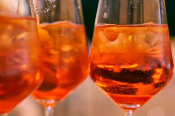 these spritzes in wine glasses get their lovely red-orange hue from orange-flavored aperol bitters.