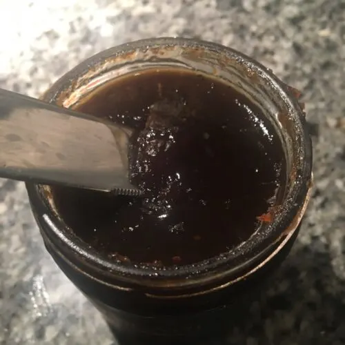 8 Molto Bene Ideas Staycation Italian Night Theme Party scooping onion jam from a jar with a knife for the base of our easy bruschetta