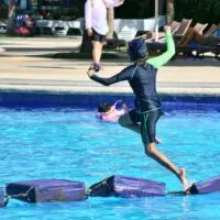 A boy jumps into a hotel pool on a resort vacation.