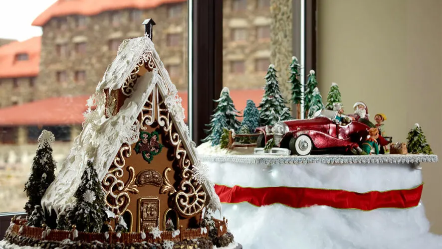 a swiss chalet is covered in snow while santa an his elves drive a red convertible through snowy woods, two entrants in the omni grove inn's annual gingerbread competition.