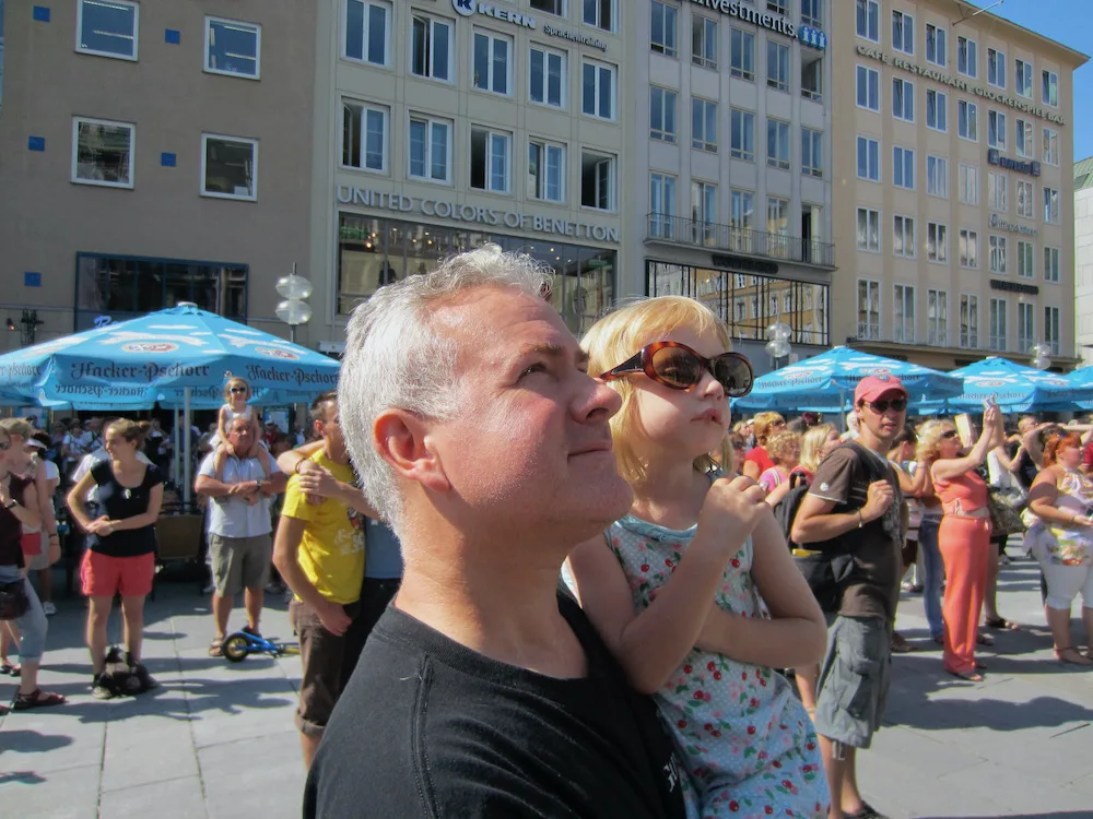 dad and daughter in the marienplatz in munich, looking up at the glockenspiel.