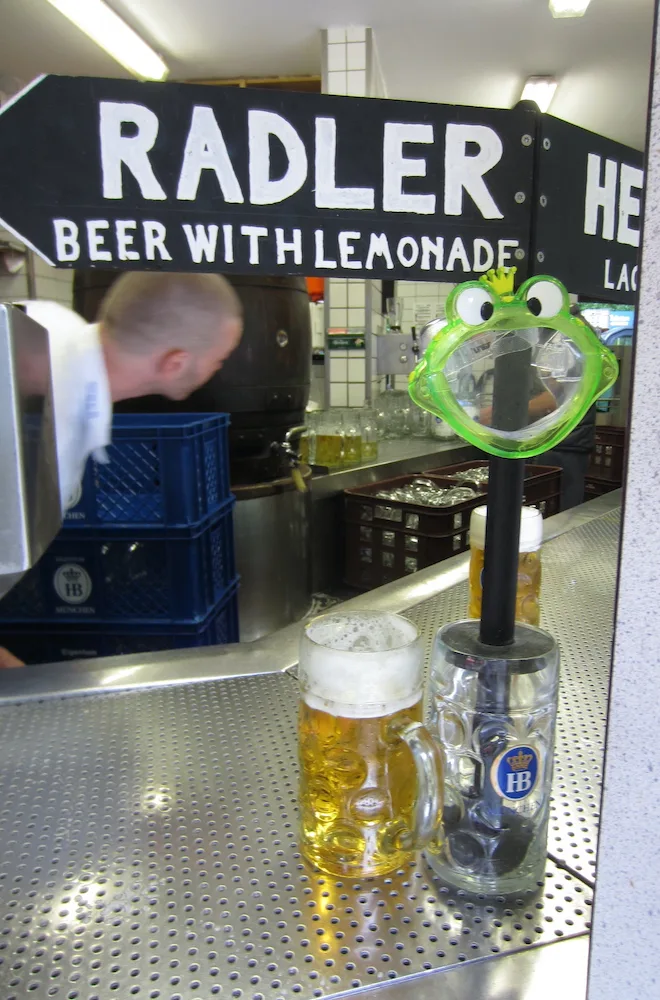 a beer garden stand in munich serves up radlers and helles beer to customers.