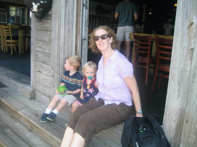 Red's ice house is a casual low country fish shack in shem creek, near charleston. 2 kids and a woman sit on the steps outside waiting for their po'boys.