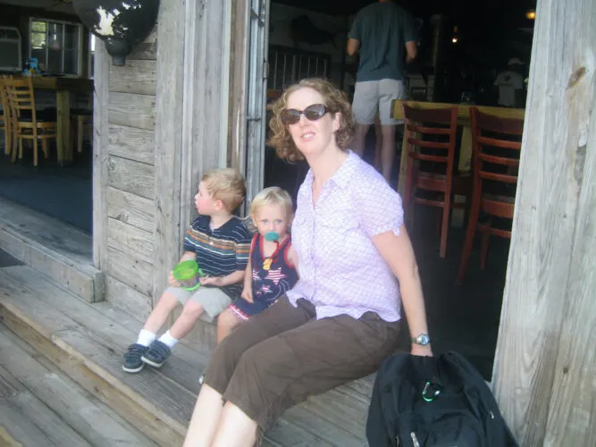 red's ice house is a casual low country fish shack in shem creek, near charleston. 2 kids and a woman sit on the steps outside waiting for their po'boys.