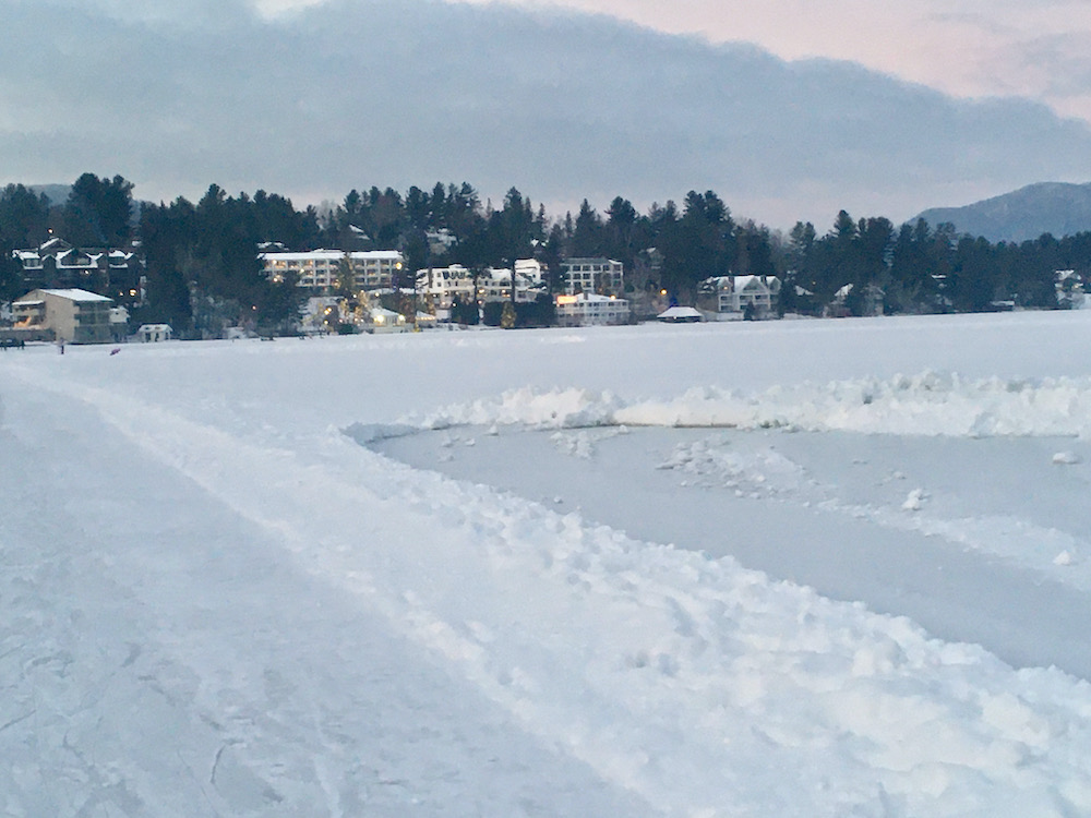A view of the town of lake placid at dusk from across mirror lake.