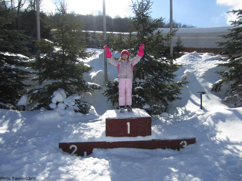 a girl tries out the medal podium at mt. hoevenberg in the adirondacks.