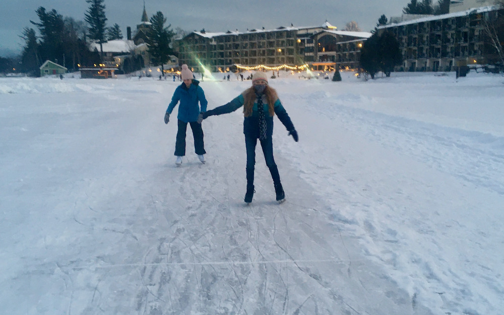 Two teens sk along a cleared trail on frozen mirror lake in lake placid.
