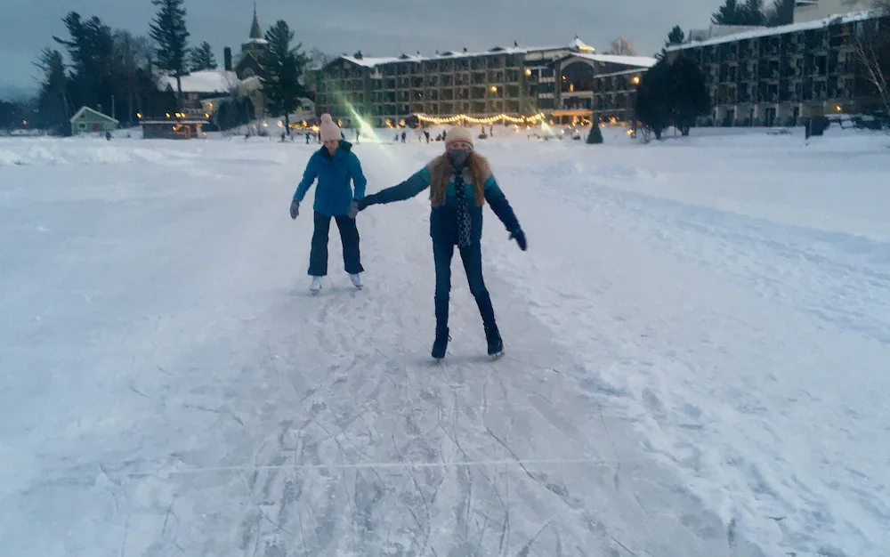 two teens sk along a cleared trail on frozen mirror lake in lake placid.