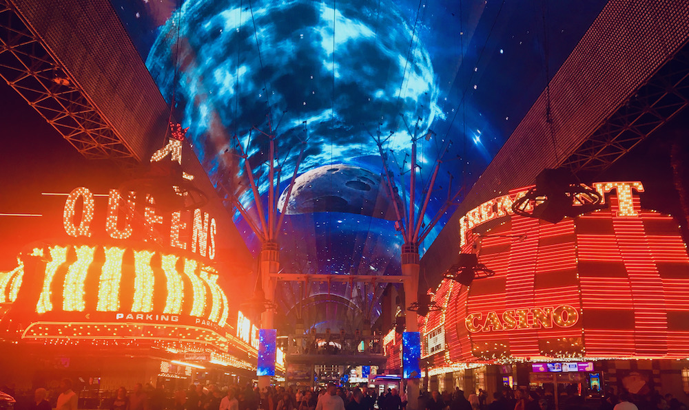 Neon signs for classic downtown las vegad hotels and a turbulennt blue sky across the dome of the fremont street experience