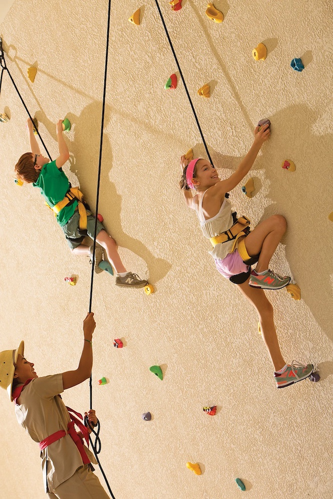 the explorers club kids program at dreams las mareas has a climbing wall where staff will belay young climbers.