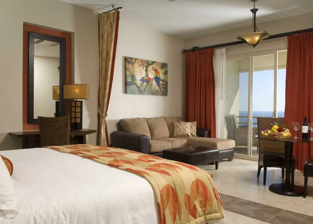 the junior suites at parador resort hotel have large beds, pull-out couches, a table and a balcony with ocean views.